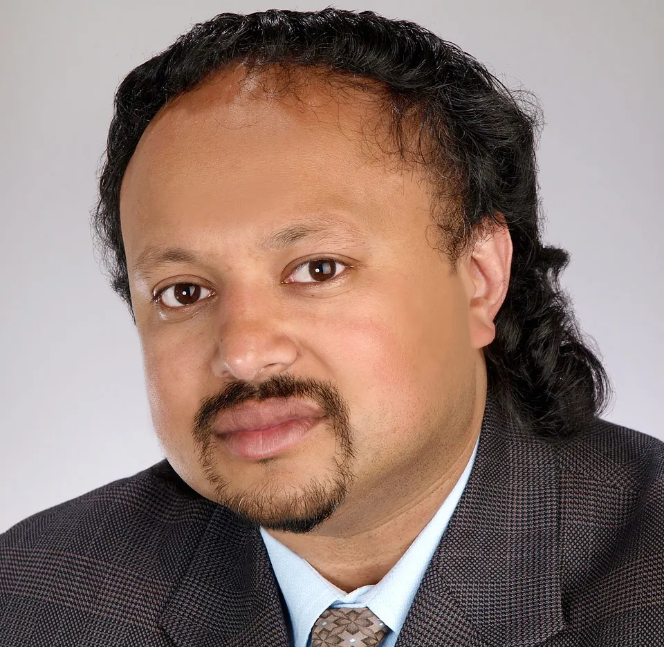 Headshot of a man with black curly hair.