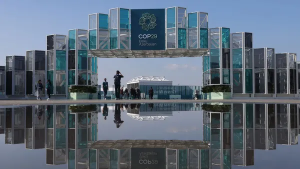 People are reflected in a puddle outside the COP29 conference venue