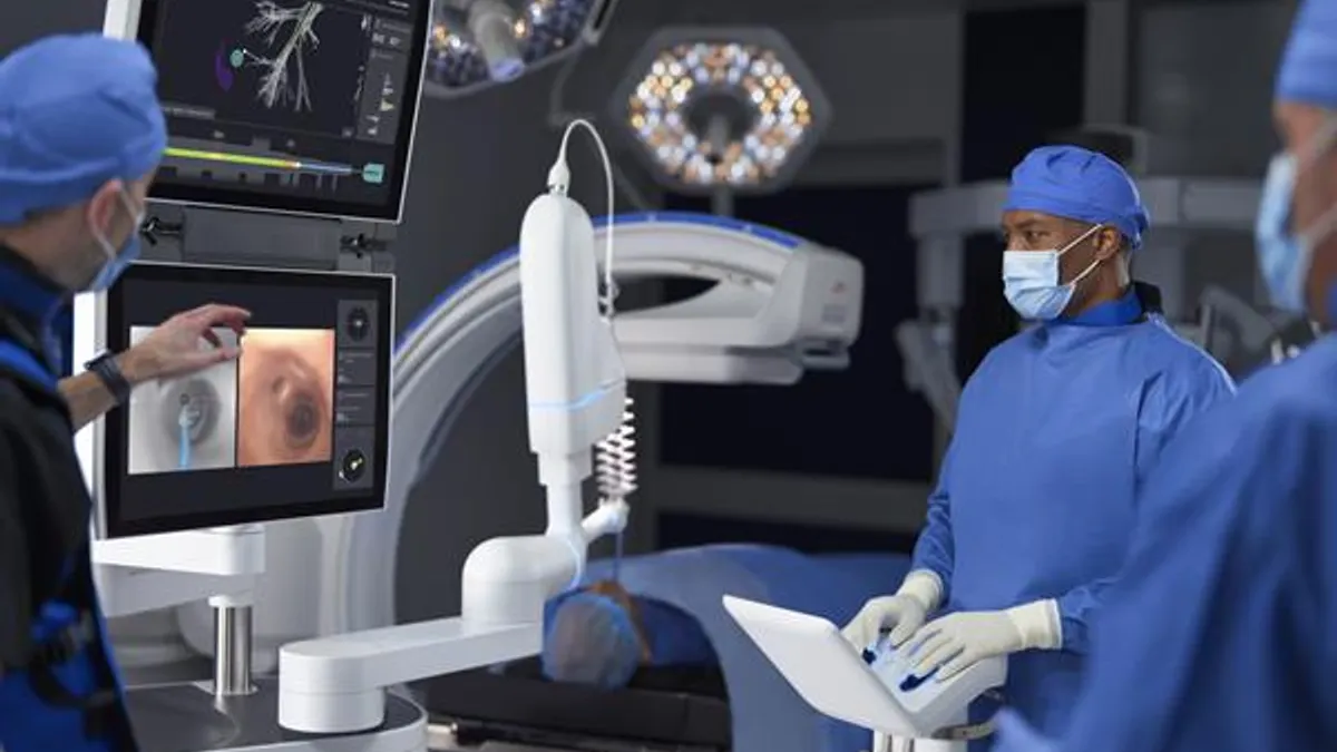 Three people view Intuitive Surgical's Ion robotic system during a procedure setup.