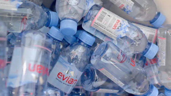 Close-up shot of many Evian water bottles in a haphazard pile.