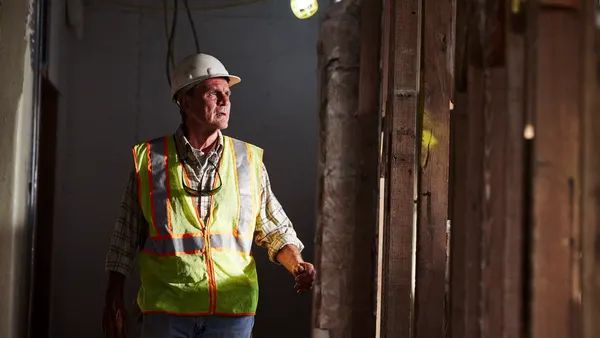 A construction worker in a white safety hat and yellow work jacket.