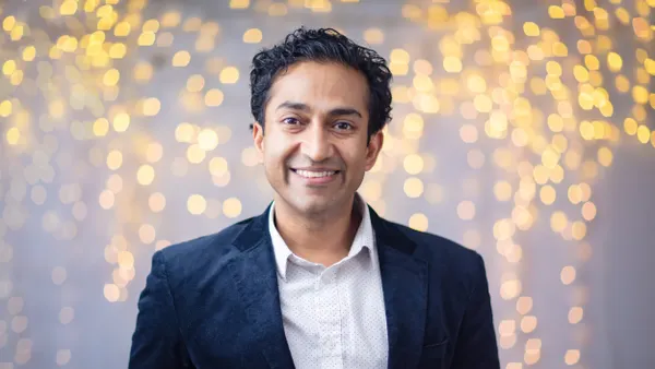 A smiling portrait of Vinay Prasad, the director of CBER, set against a sparkling light background.