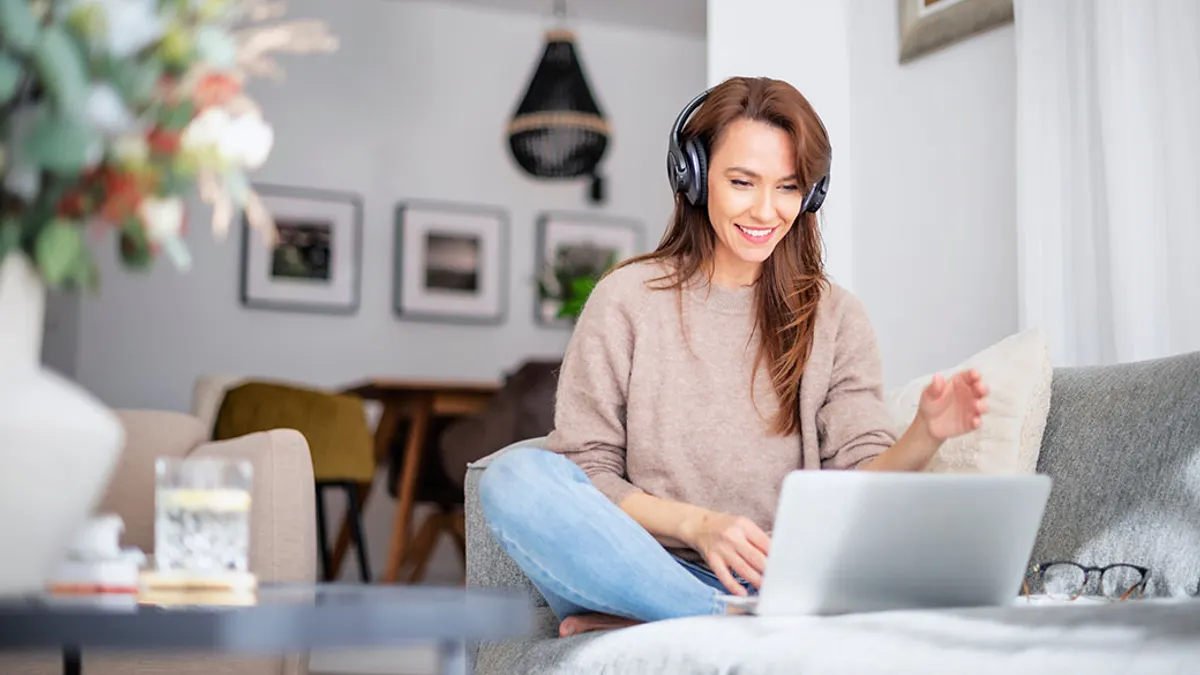Woman with headphone using a laptop while having video call.