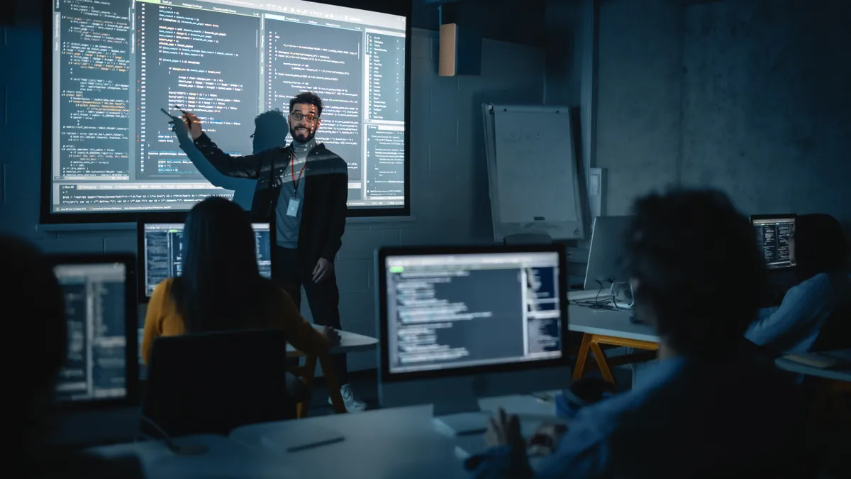 Teacher Giving Computer Science Lecture to Diverse Multiethnic Group of Female and Male Students in Dark College Room.