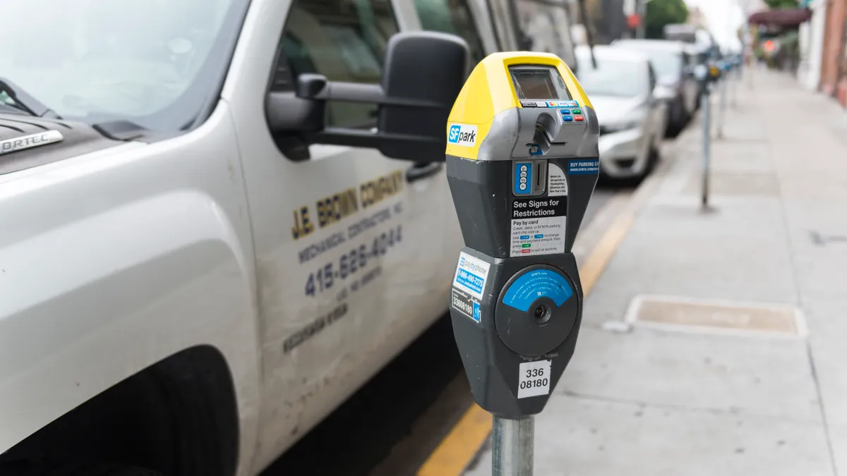 Closeup of parking meter in front of cars parked on the curb