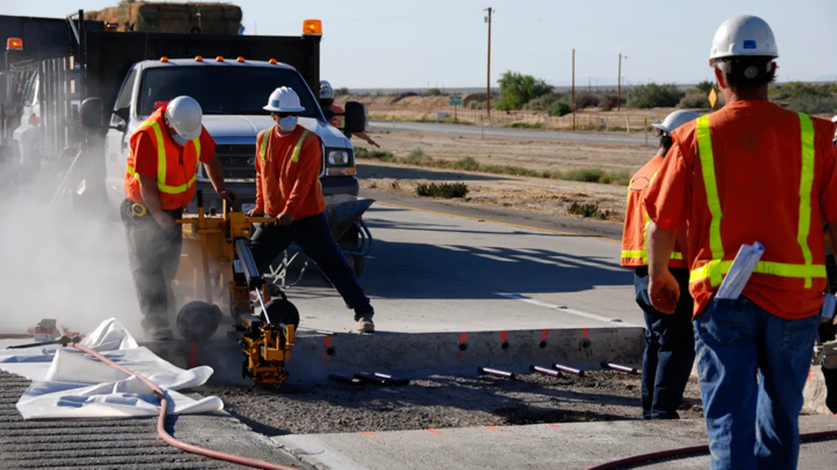 highway workers pour asphalt on a road project