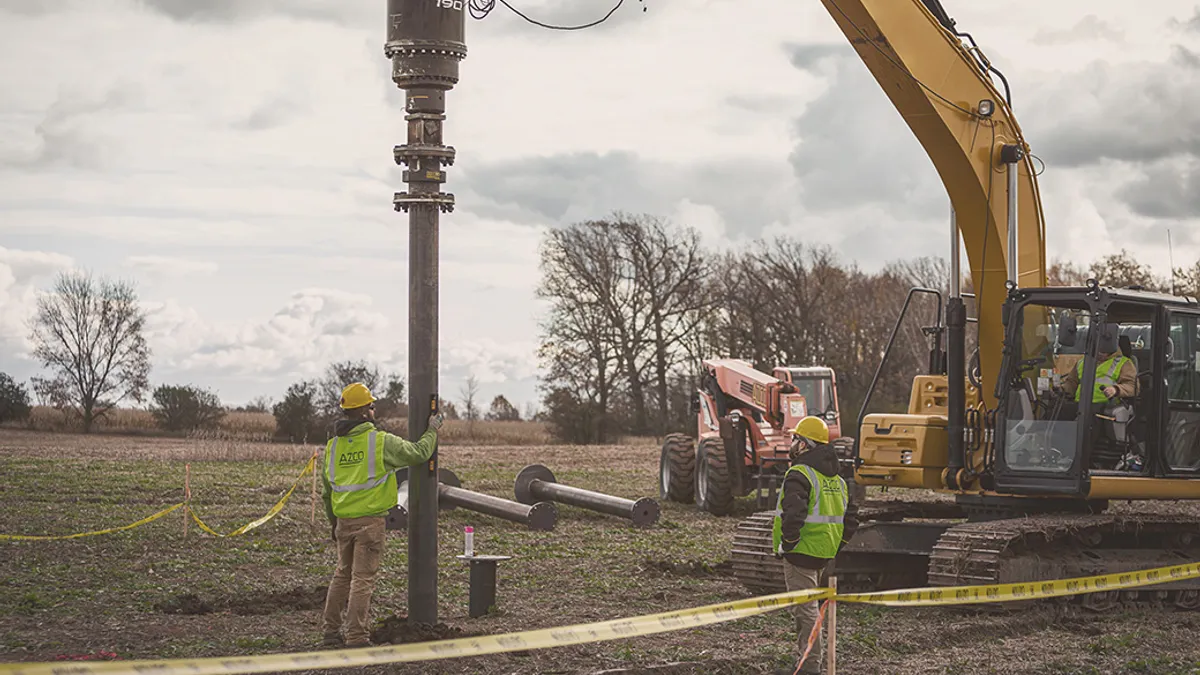 Construction workers using heavy equipment to install Helical piles