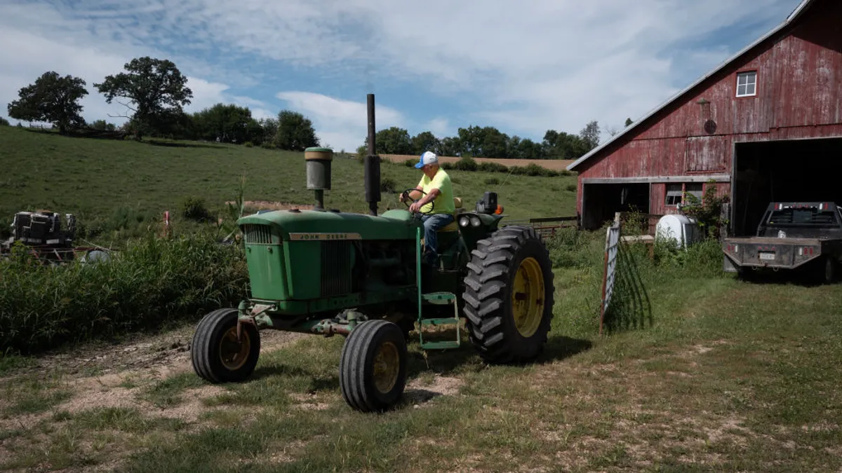 A farmer drives his tractor out of a red barn