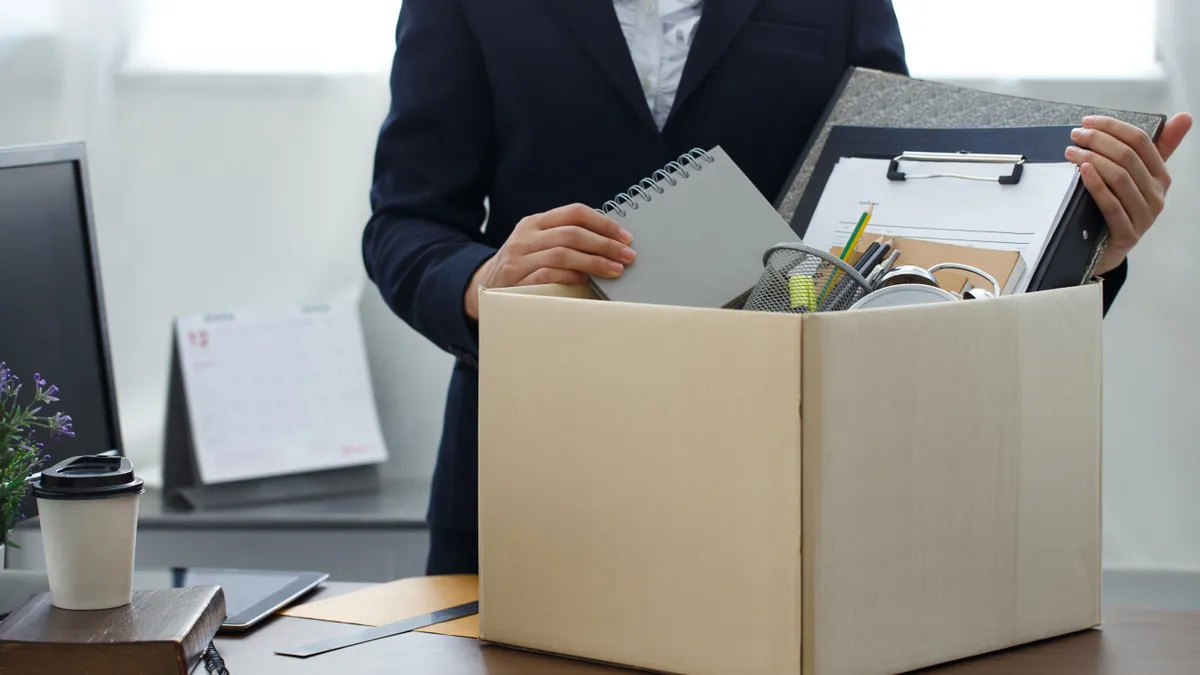 A person whose job has been cut collects their belongings