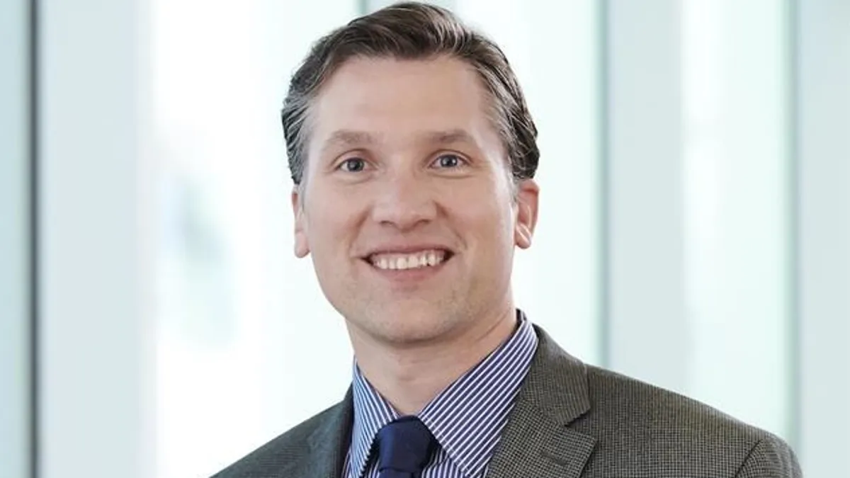 A professional photo of Egeland smiling and standing in front of a window.