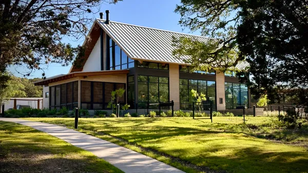 A low-rise wooden structure in a green field.