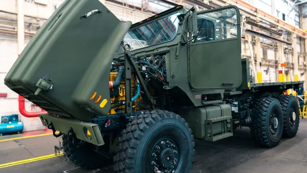 A dark junble green medium tactical vehicle's hood opened.