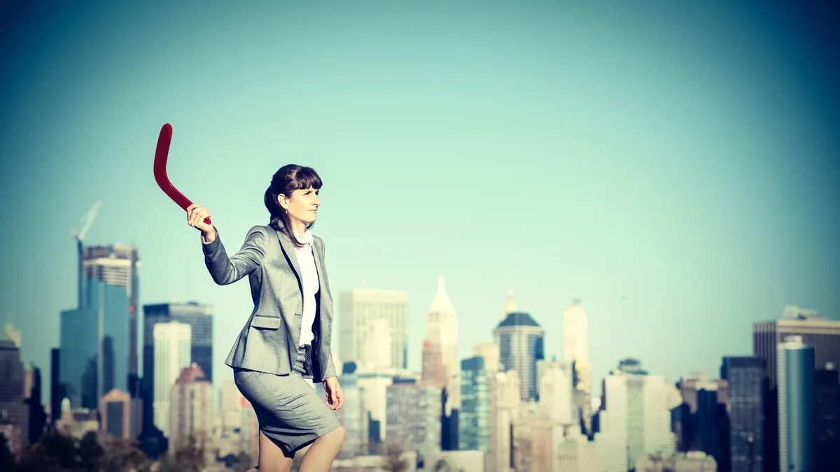 Businesswoman throws a boomerang.