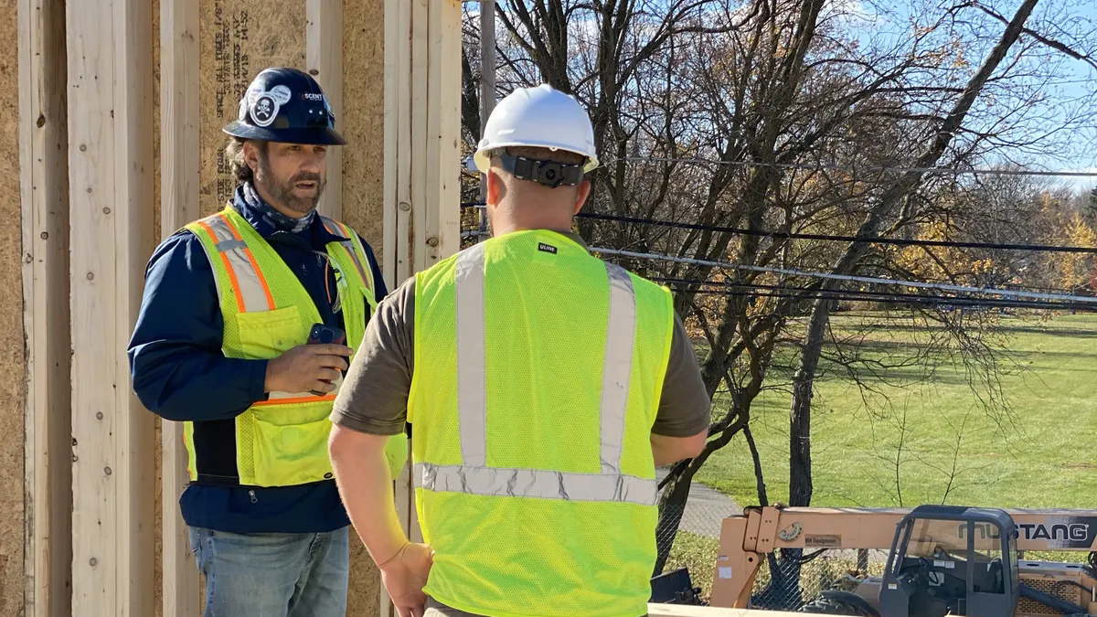 Two people having a conversation in construction safety gear on a jobsite.