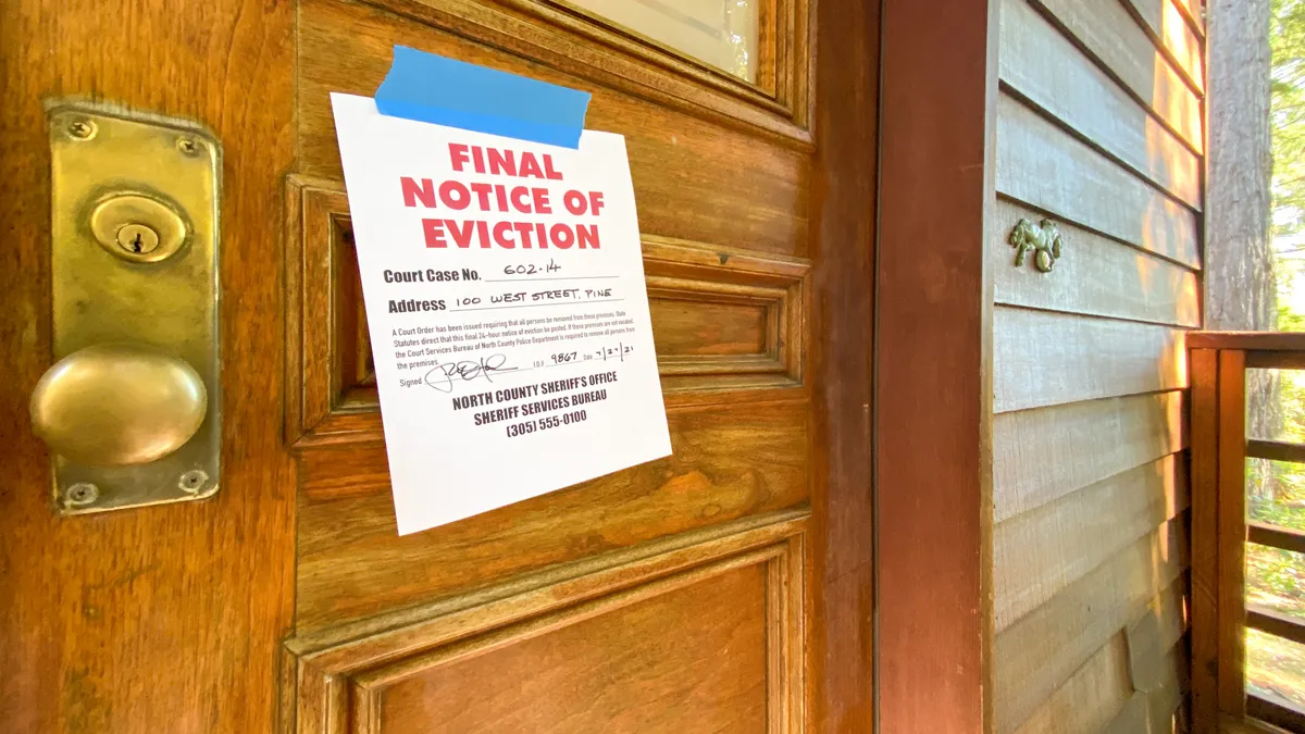 Eviction notice on door of house with brass door knob.