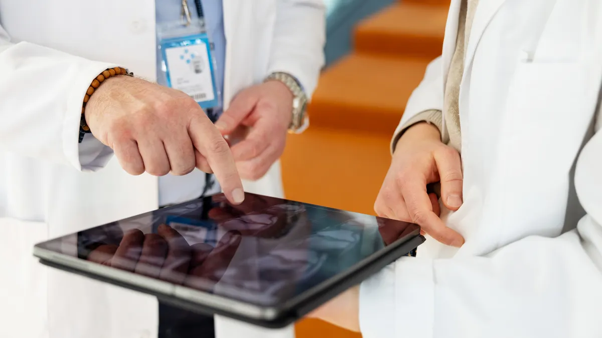 Close view of two medical professionals pointing at tablet screen during clinical review