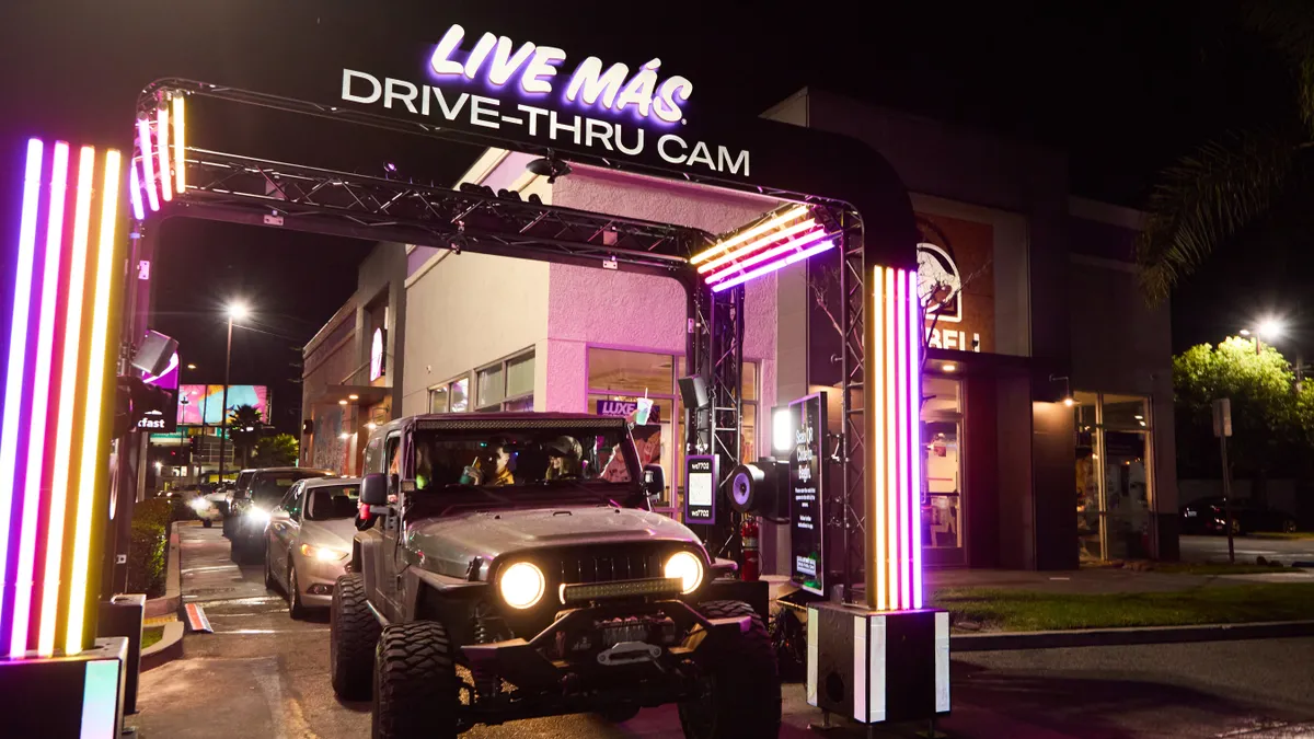 A car sits underneath Taco Bell's new drive-thru camera stations, which are decorated in neon signage