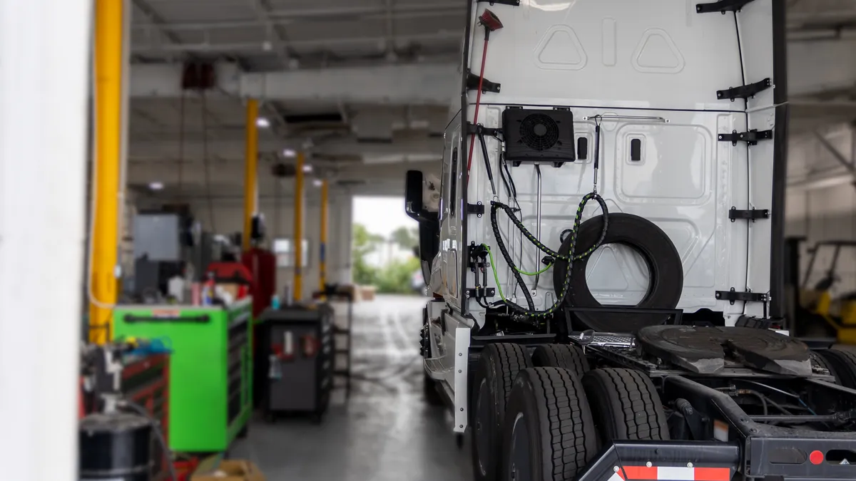 A tractor inside the garage of a truck repair shop.