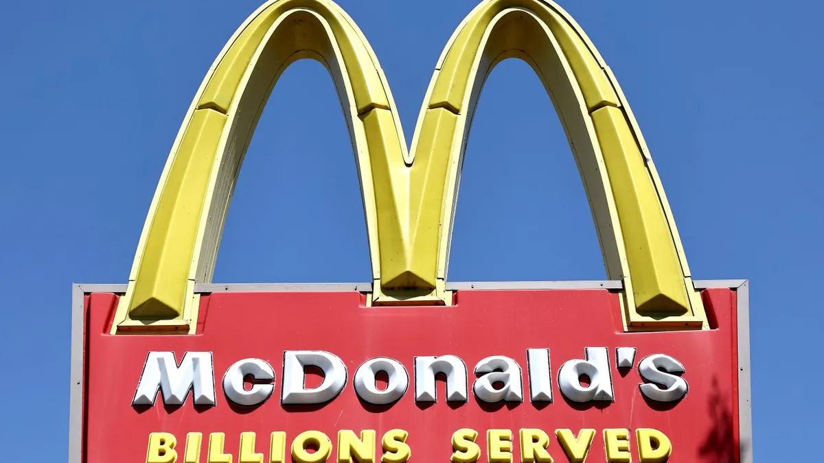 A photograph of a red and yellow sign with a giant yellow "M" above a red box that says "McDonald's Billions Served."