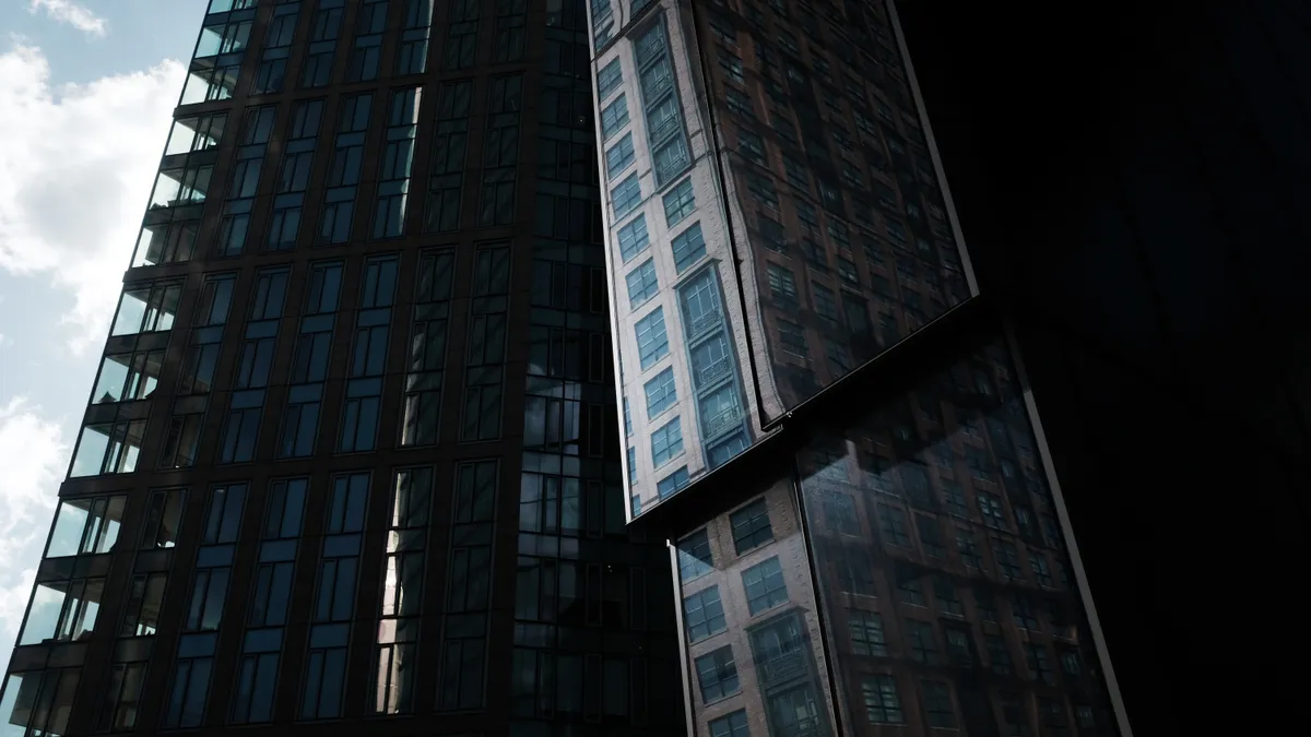 Photo looking up at a high-rise, glass apartment building.