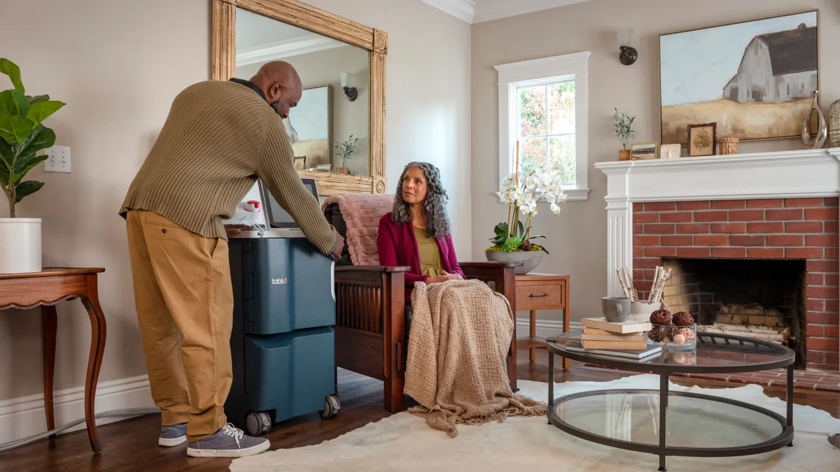 Outset Medical's Tablo dialysis system is shown with two people in a living room.