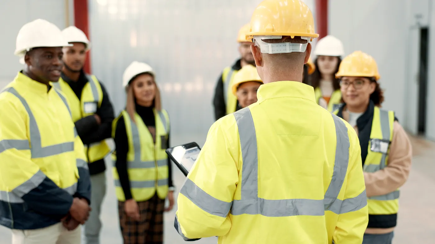 young workers in hard hats listen to a person training them