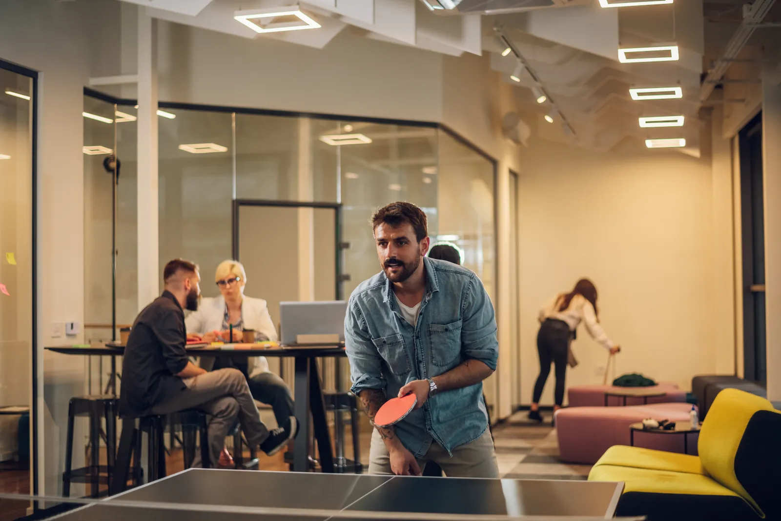 An employee plays table tennis in a break room.