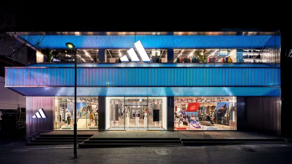 A blue-lit Adidas storefront at night.