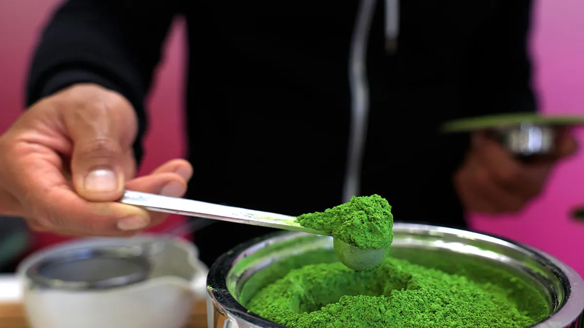 A barista is seen in a close up shot scooping matcha powder