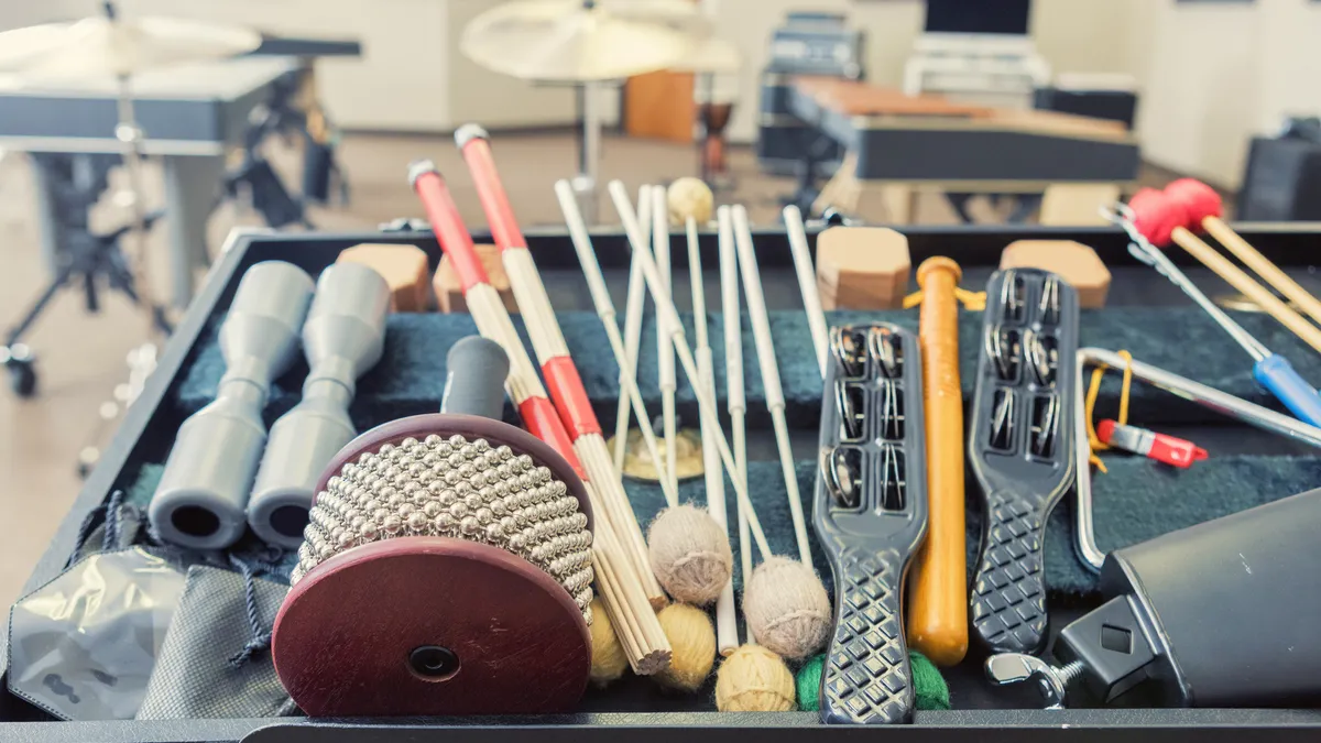 This is a still life photo of percussion instruments in a music studio. Focus is on an open case of hand held percussion instruments in the foreground.