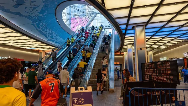 World Cup bound soccer fans stream past signs up an escalator and stairs at Penn Station in New York City.