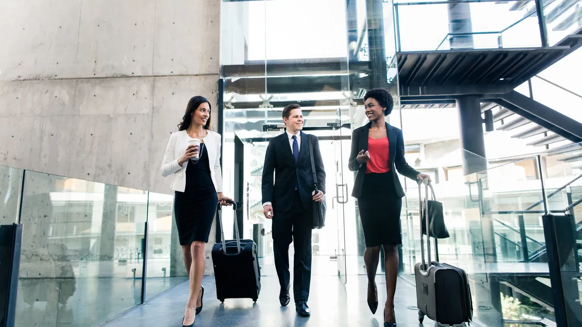 Coworkers walking side by side with suitcase in hand