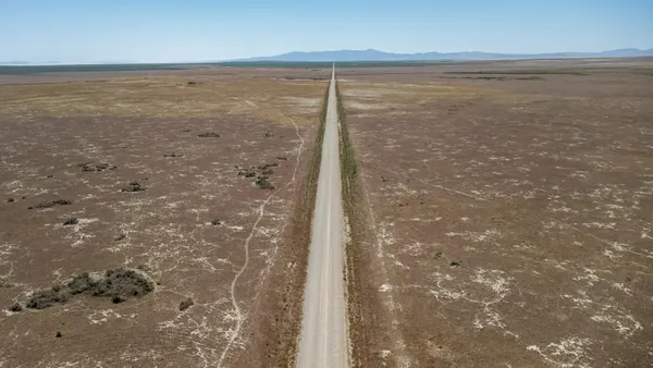 An aerial view of a road cutting through a massive flat landscape.