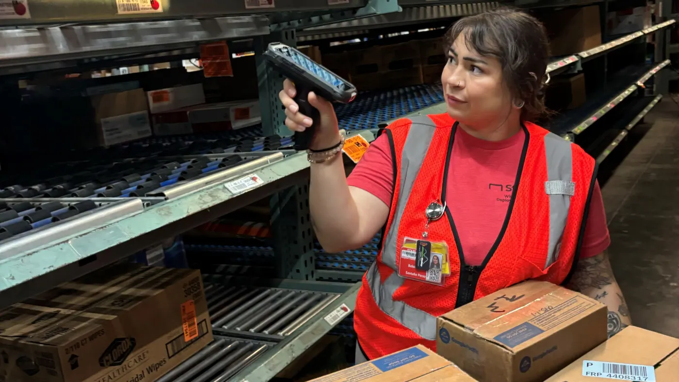 An employee scans a product inside of a Staples warehouse.