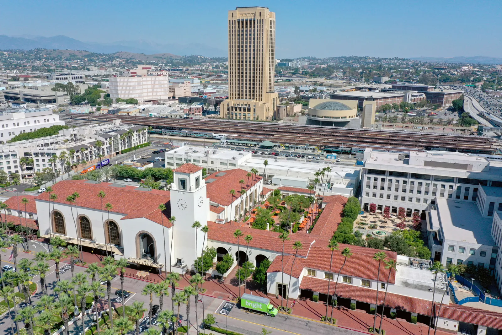 Aerial view of large white building with red tile roof and other buildings in the background.