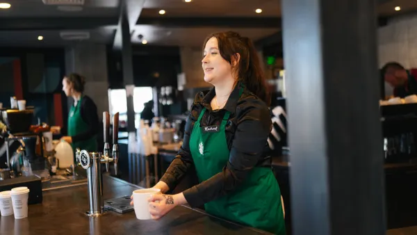 A Starbucks worker in a green apron and a black shirt.