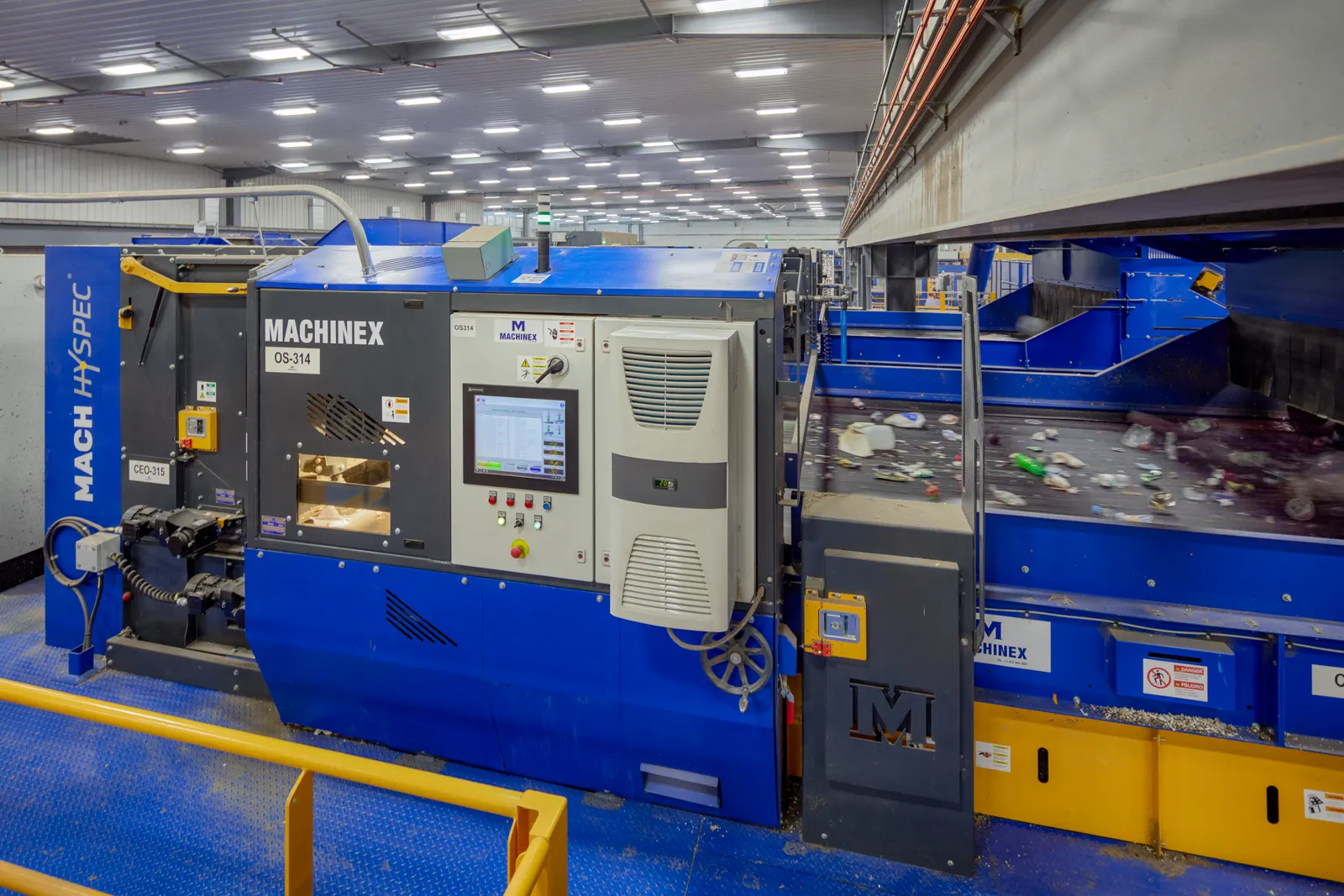 A large piece of equipment in a recycling facility features Machinex branding.