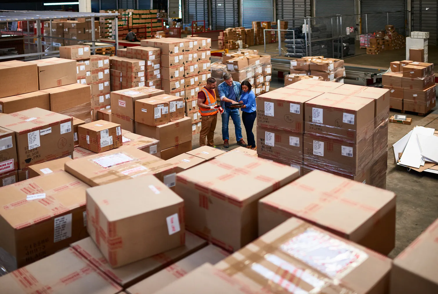 People at work in a large warehouse full of boxes.