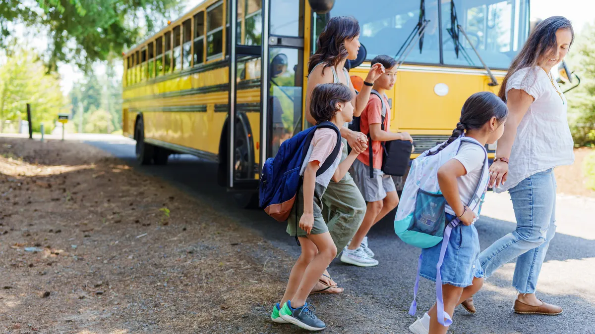 Two moms greet their kids and walk with them home from the school bus stop in their rural neighborhood.