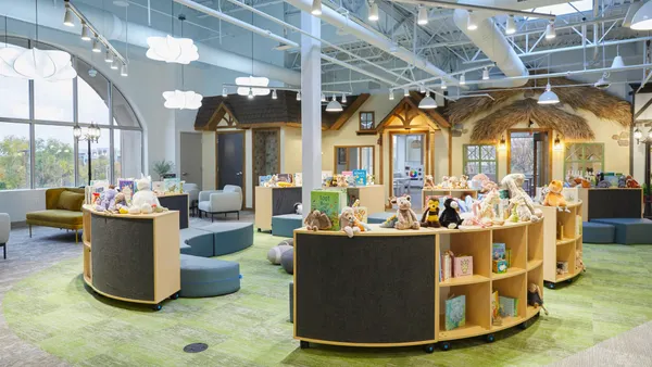 A view into a large open room with children's bookshelves and seating, and faux storefronts in the background.