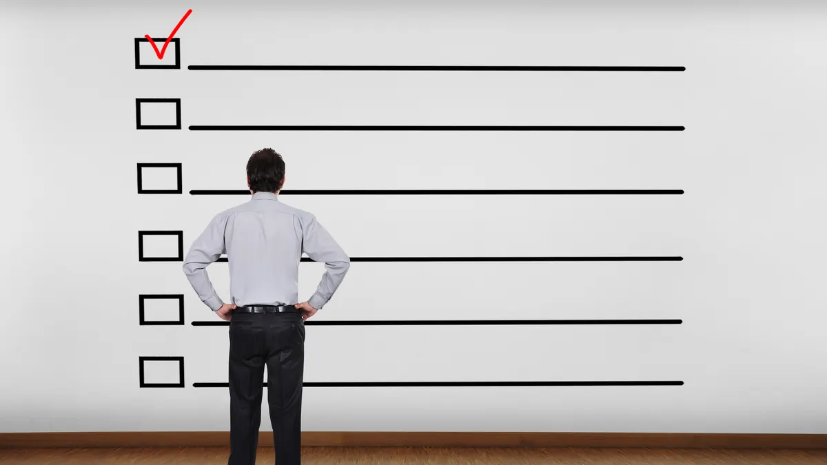 Businessman in office looking at wall with checklist