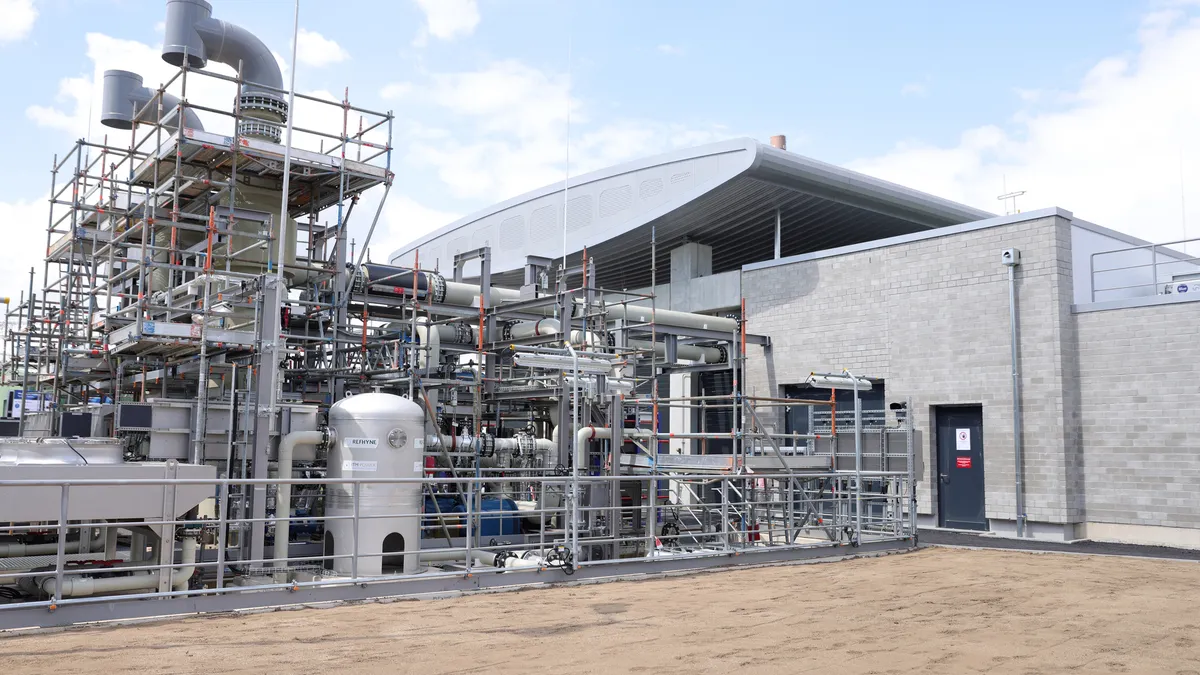 A general view of a facility with a vast amount of tubes and ducts on the exterior of a grey brick building.