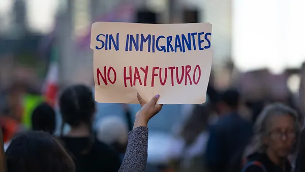The sign reads "SIN IMMIGRANTES / NO HAY FUTURO" which means "WITHOUT IMMIGRATIONS, THERE IS NO FUTURE."