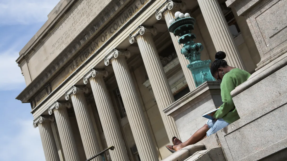 A person sits outside a Columbia University library building.