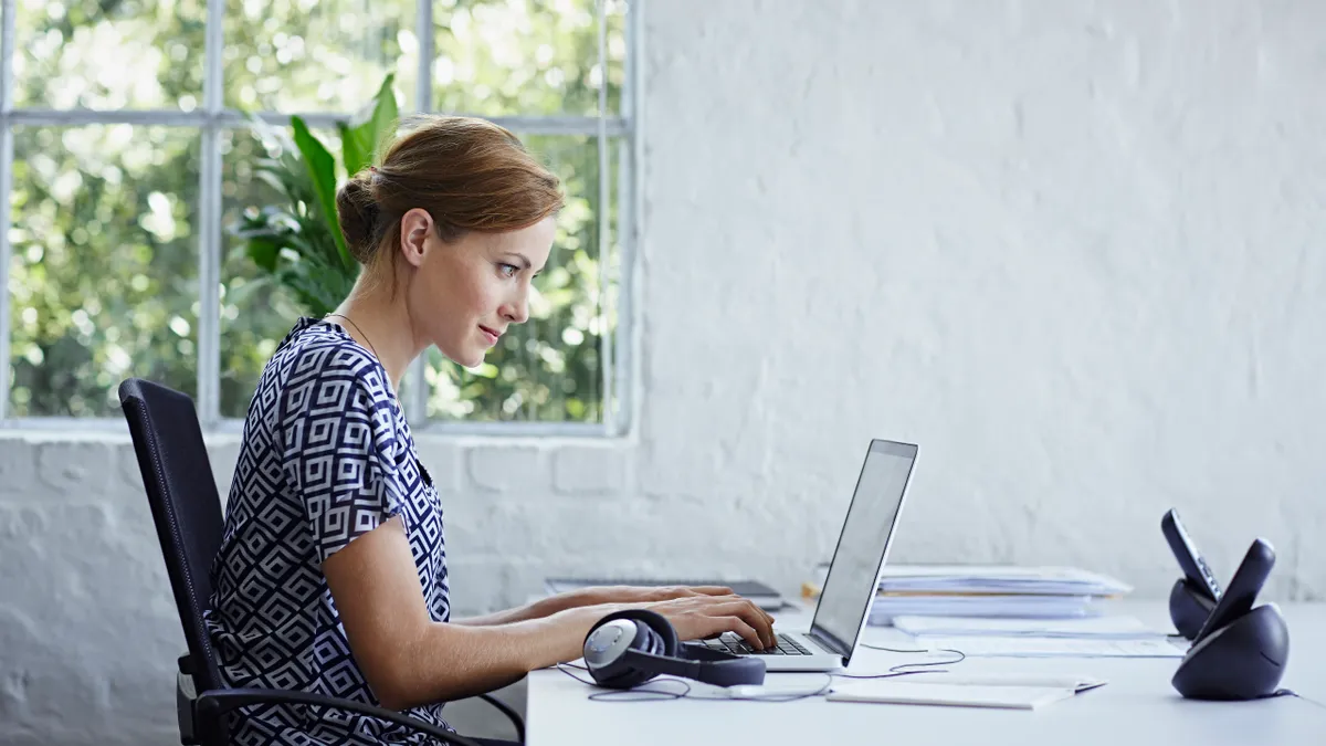 A person typing on the laptop at a desk table.