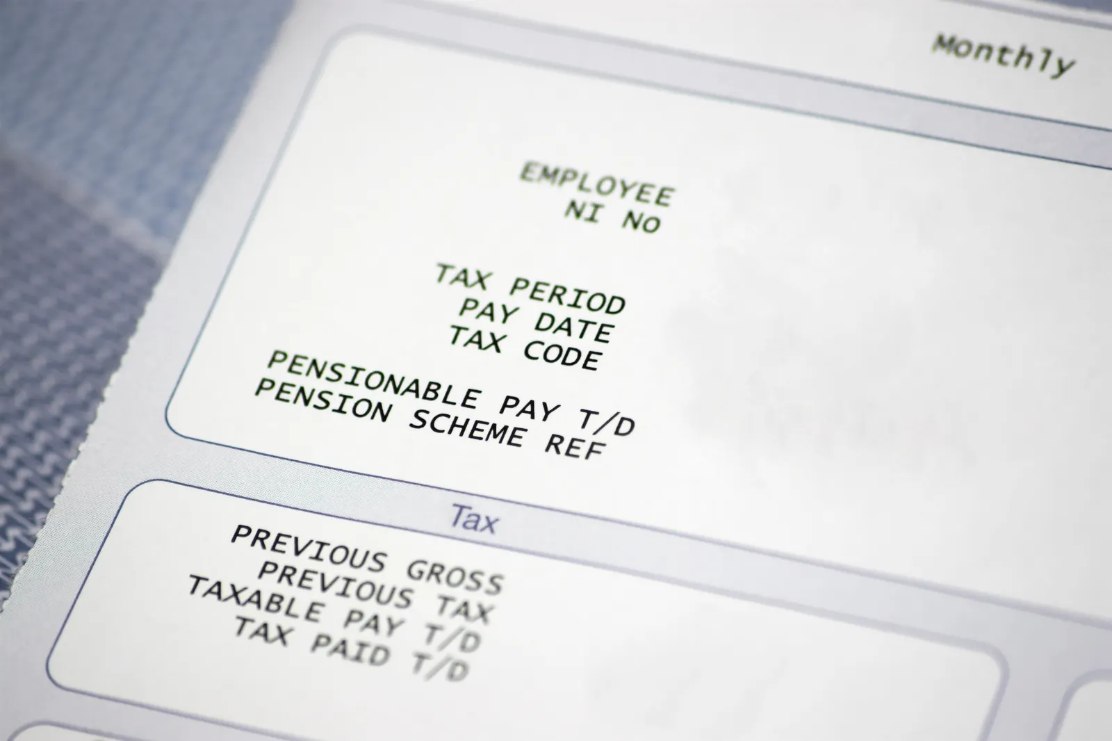 A close-up of a paper pay slip with tax and pension information.