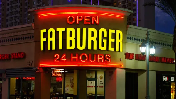 A nighttime image of a beige building with a sign that says Fatburger open 24 hours.