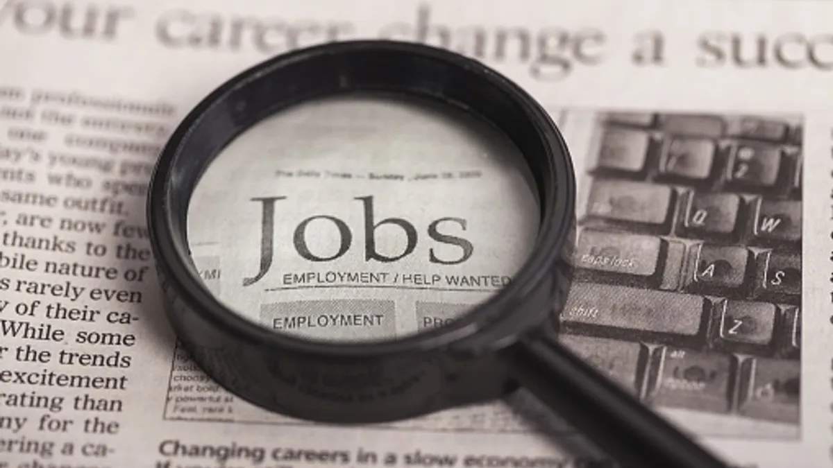 Magnifying glass highlights the word, "Jobs," on a newspaper