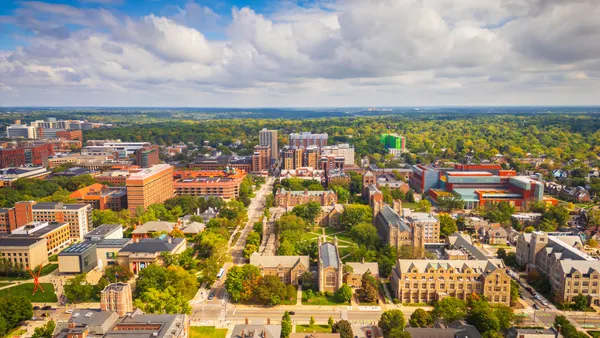 An aerial view of different sized buildings intermixed with roads and trees