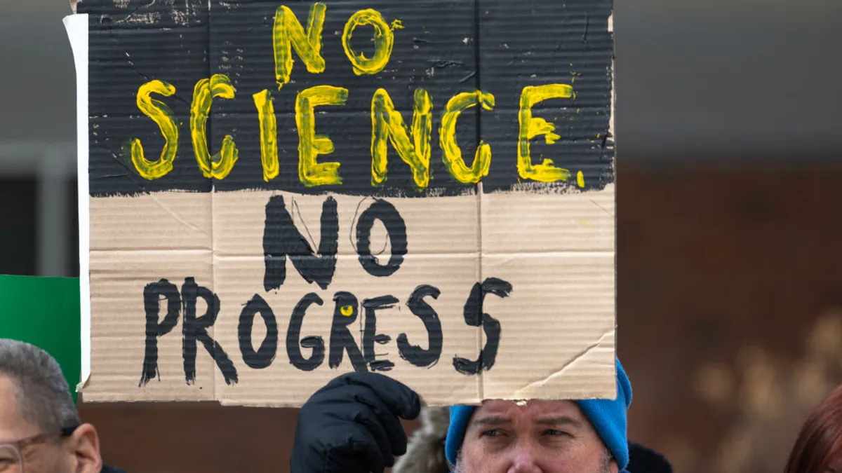 A protester holds up a sign reading, in all caps, "No science no progress."